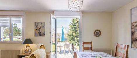 A room with a bed, a table, a chair, a lamp, and a view of the outdoors.
