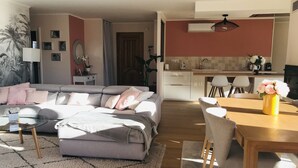 Een woonkamer met een bank, een salontafel, en een eethoek met een tafel en stoelen.