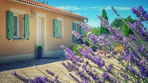 A house with a tiled roof, green shutters, and a gravel driveway.