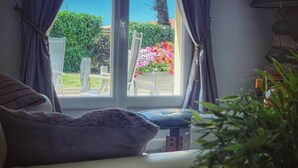 A room with a sofa, a window with curtains, a small table, and a potted plant.