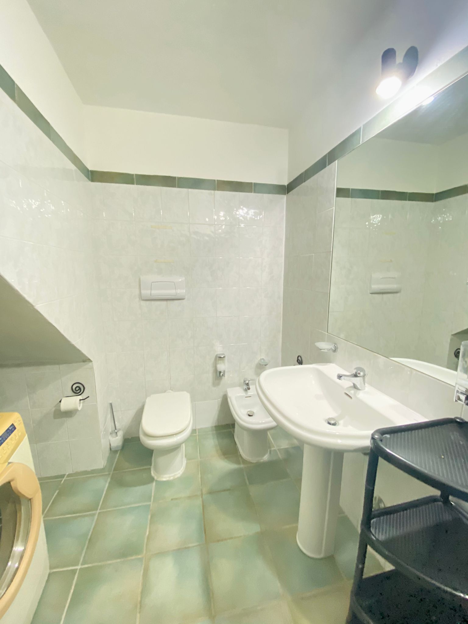 A bathroom with a toilet, bidet, sink, and a mirror.