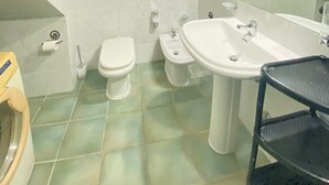 Un baño con inodoro, bidé, lavabo y espejo.