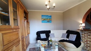 Un salon avec une table basse en verre, un canapé, un meuble et un tableau accroché au mur.