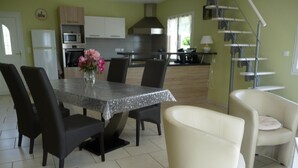 Una cocina moderna con comedor, que incluye una mesa con sillas, un florero y una escalera.