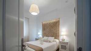 Een netjes ingerichte slaapkamer met een groot bed, twee nachtkastjes met lampen, en een decoratief hoofdeinde.