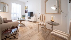 Een moderne woonkamer met een bank, een salontafel, een televisie en een decoratieve fauteuil.