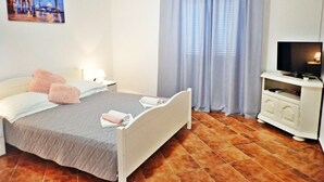 A hotel room with a bed, a television, a nightstand, and a painting on the wall. - Apartment with garden near the beach (Seline)