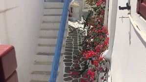 Una calle estrecha con edificios blancos, puertas azules y una escalera de piedra.