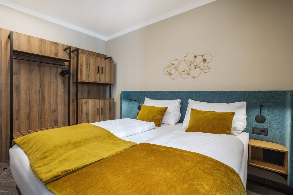 Habitación de hotel con una cama grande, un armario de madera y una lámpara fijada a la pared.