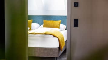 Una habitación de hotel con una cama, una manta amarilla y un cabecero azul.