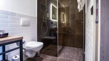 A modern bathroom with a glass-enclosed shower, a white toilet, and a wooden vanity.