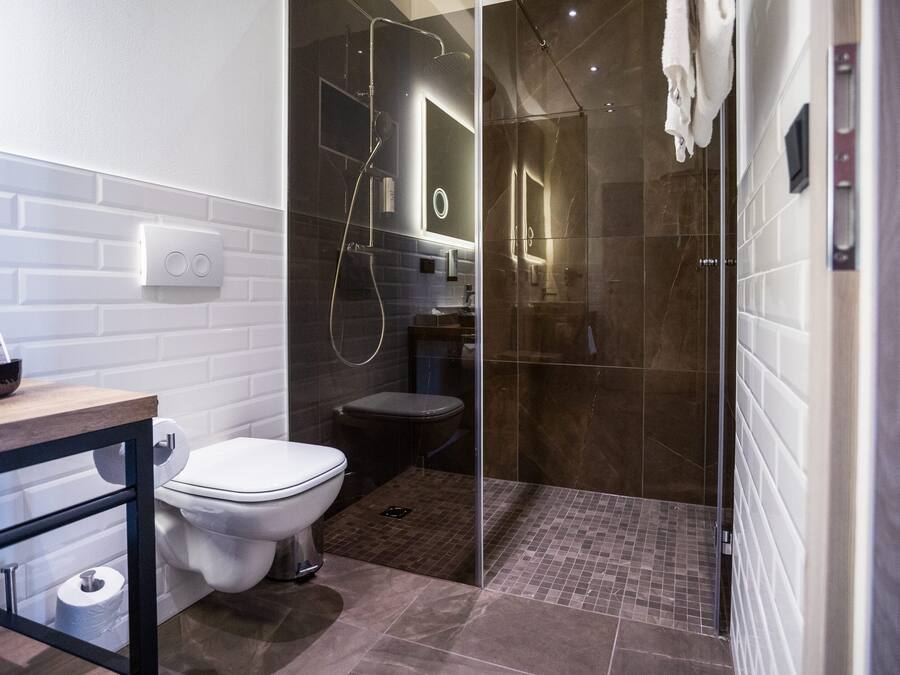Une salle de bain moderne avec une douche à parois de verre, des toilettes blanches et un meuble-lavabo en bois.