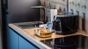 A kitchen with a black stove, a bread basket, a coffee maker, and a roll of paper towels.