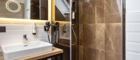 Un baño moderno con un lavamanos grande, ducha con mampara de vidrio y un espejo con luz circular.