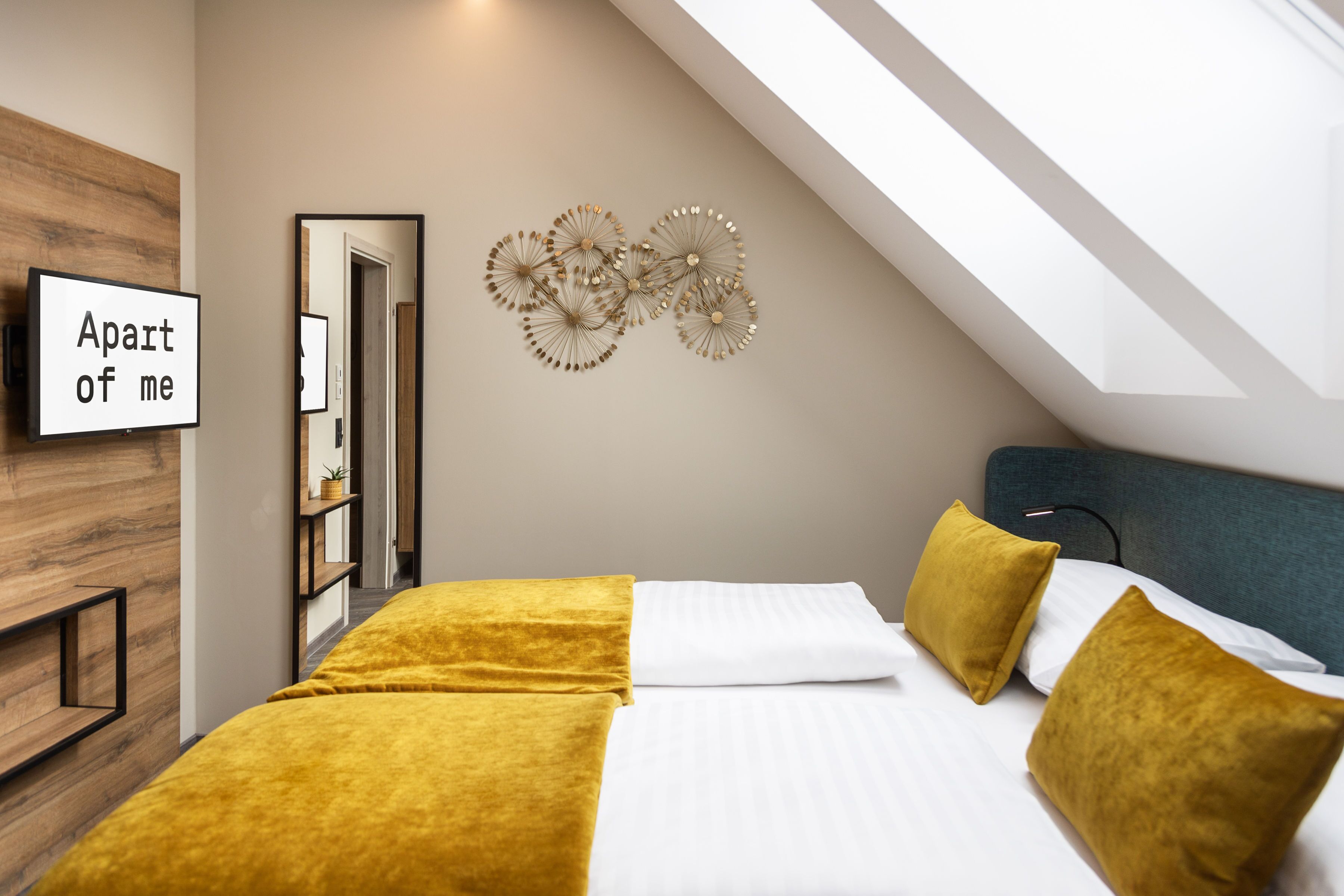 Une chambre d’hôtel moderne équipée d’un lit, de deux oreillers, d’un téléviseur fixé au mur et d’un élément décoratif mural.