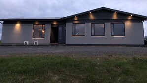 A modern two-story house with a flat roof, large windows, and a gravel driveway. - Hellnar Ocean View Villa (Hellnar)