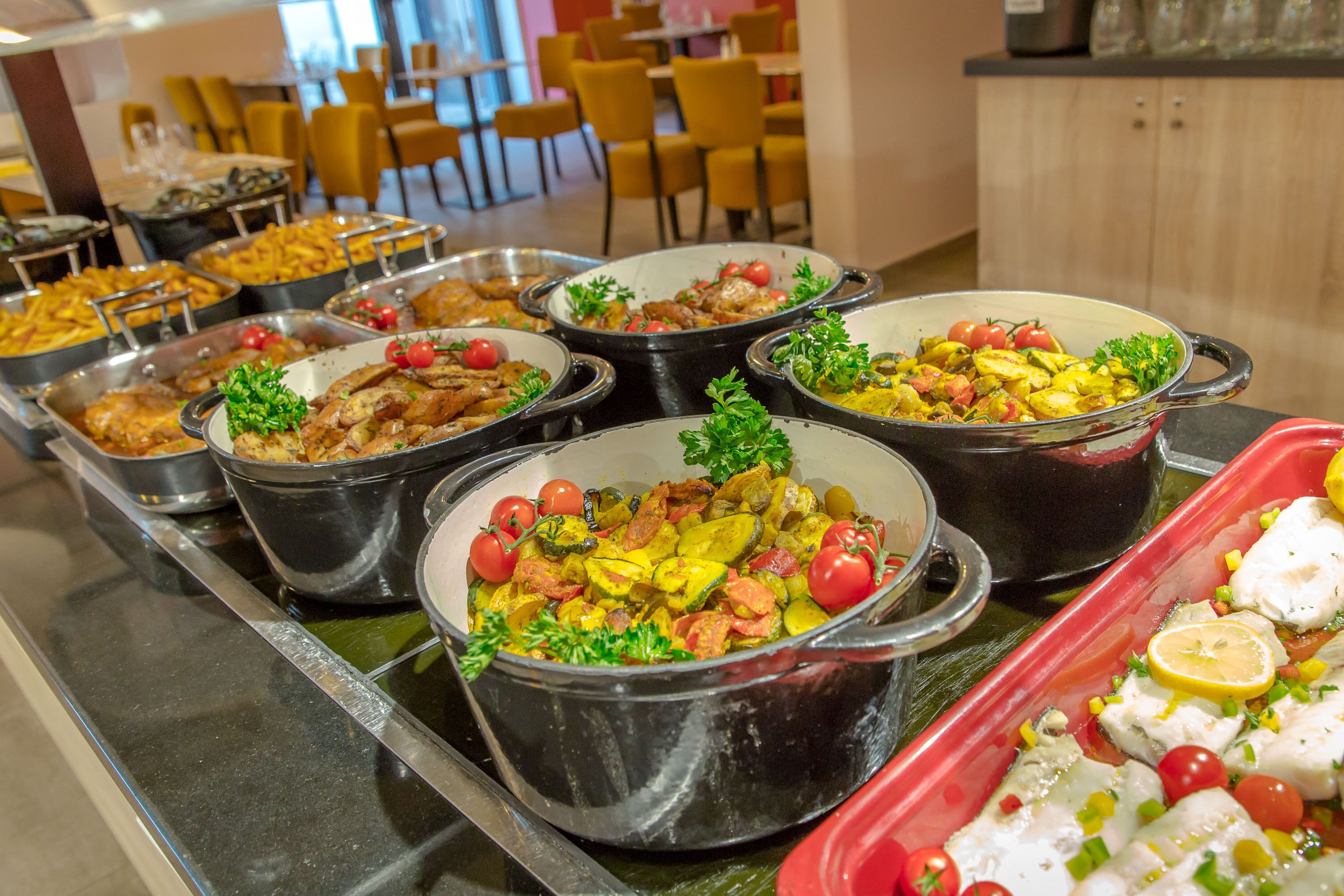 Een buffet met diverse gerechten, waaronder vis, groenten en salades.