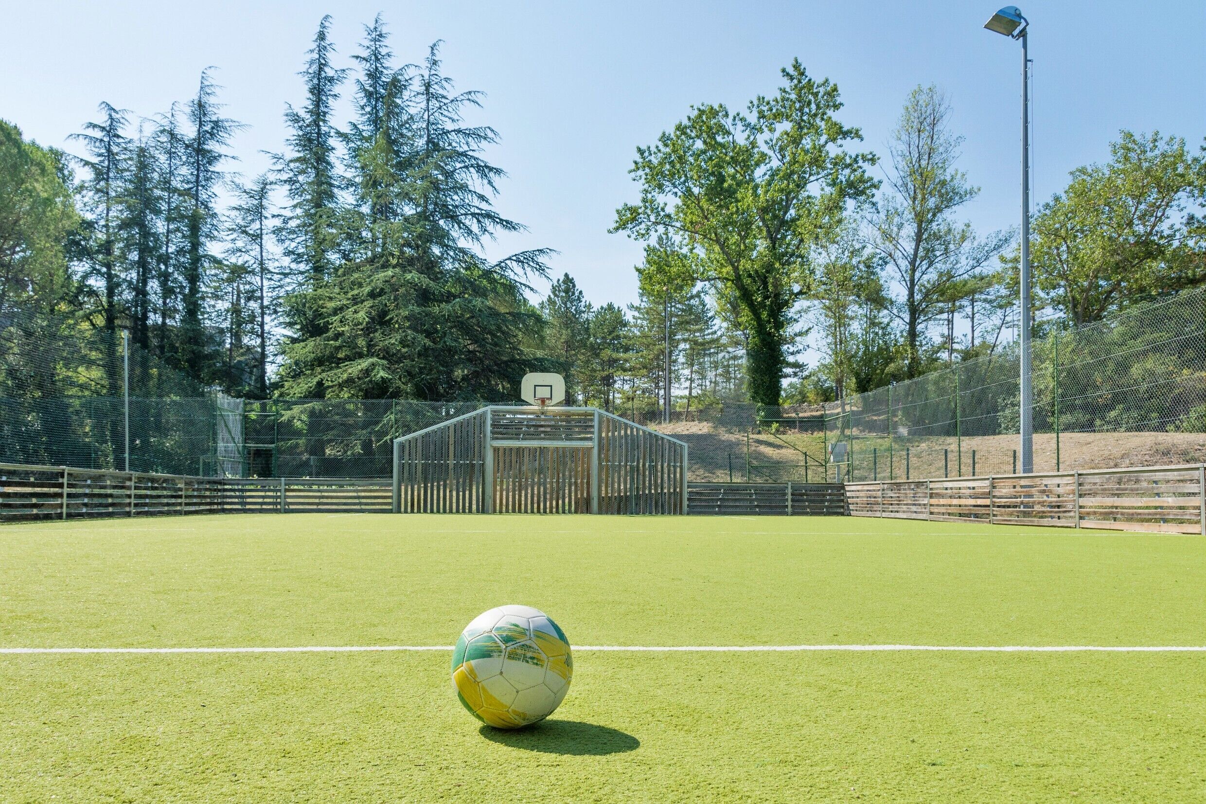A soccer field with a goalpost and a soccer ball in the foreground.