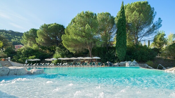 A clear blue pool with lounge chairs and umbrellas, surrounded by trees and rocks. - SOWELL HOTELS Ardèche (Grospierres)