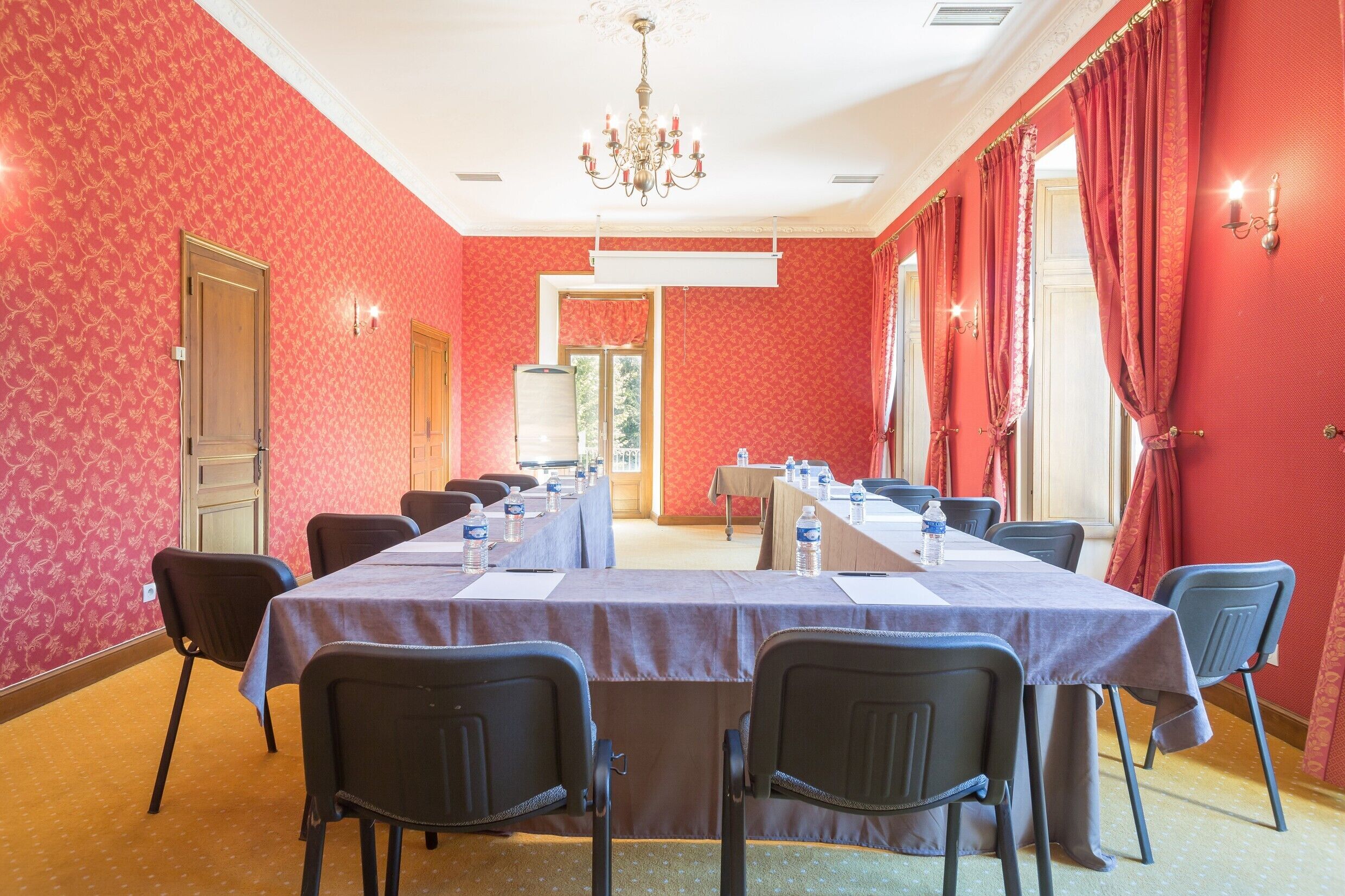 Une salle de conférence avec une longue table, des chaises et un lustre.