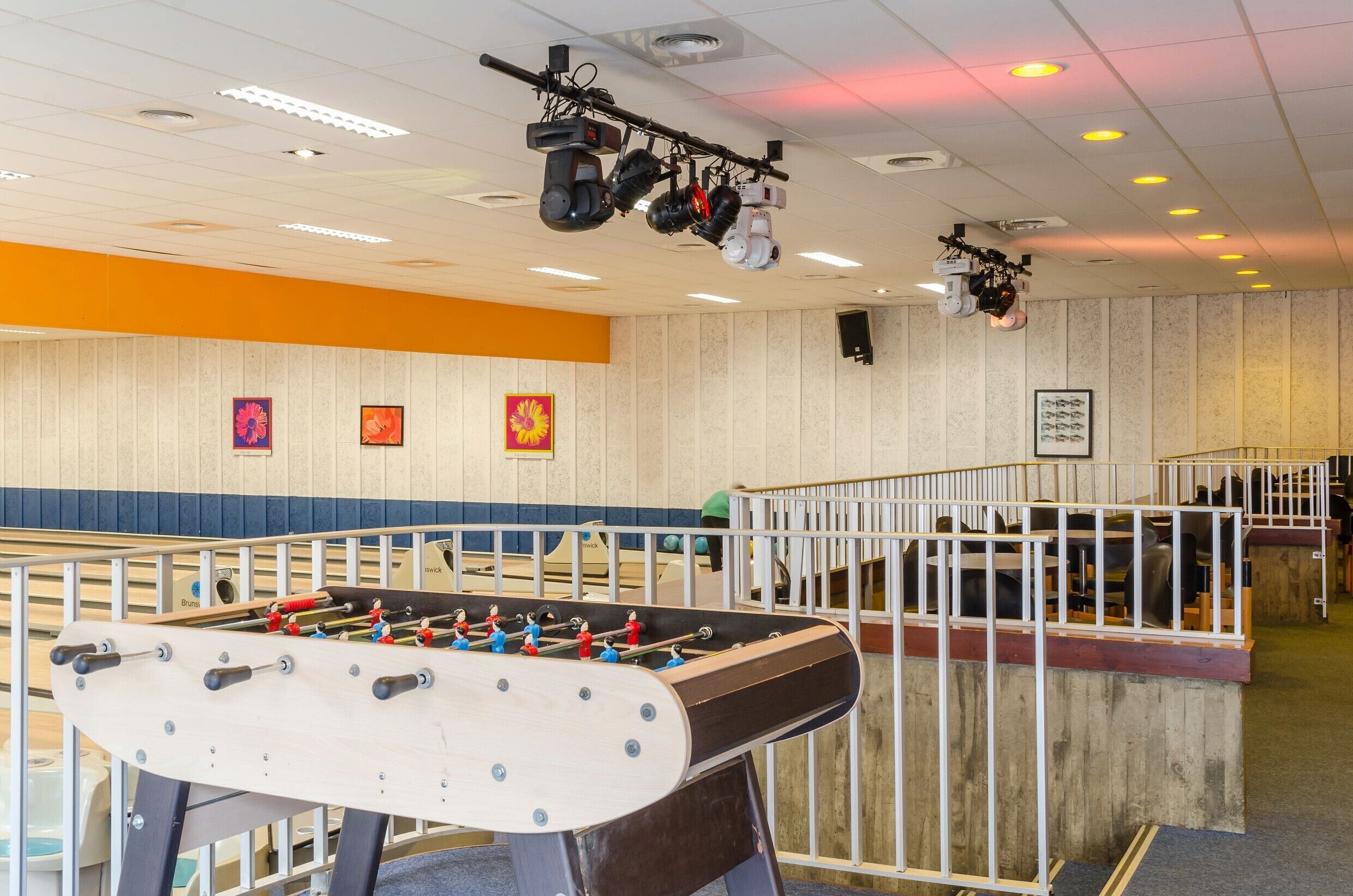 A foosball table in a room with a wooden wall and ceiling lights.