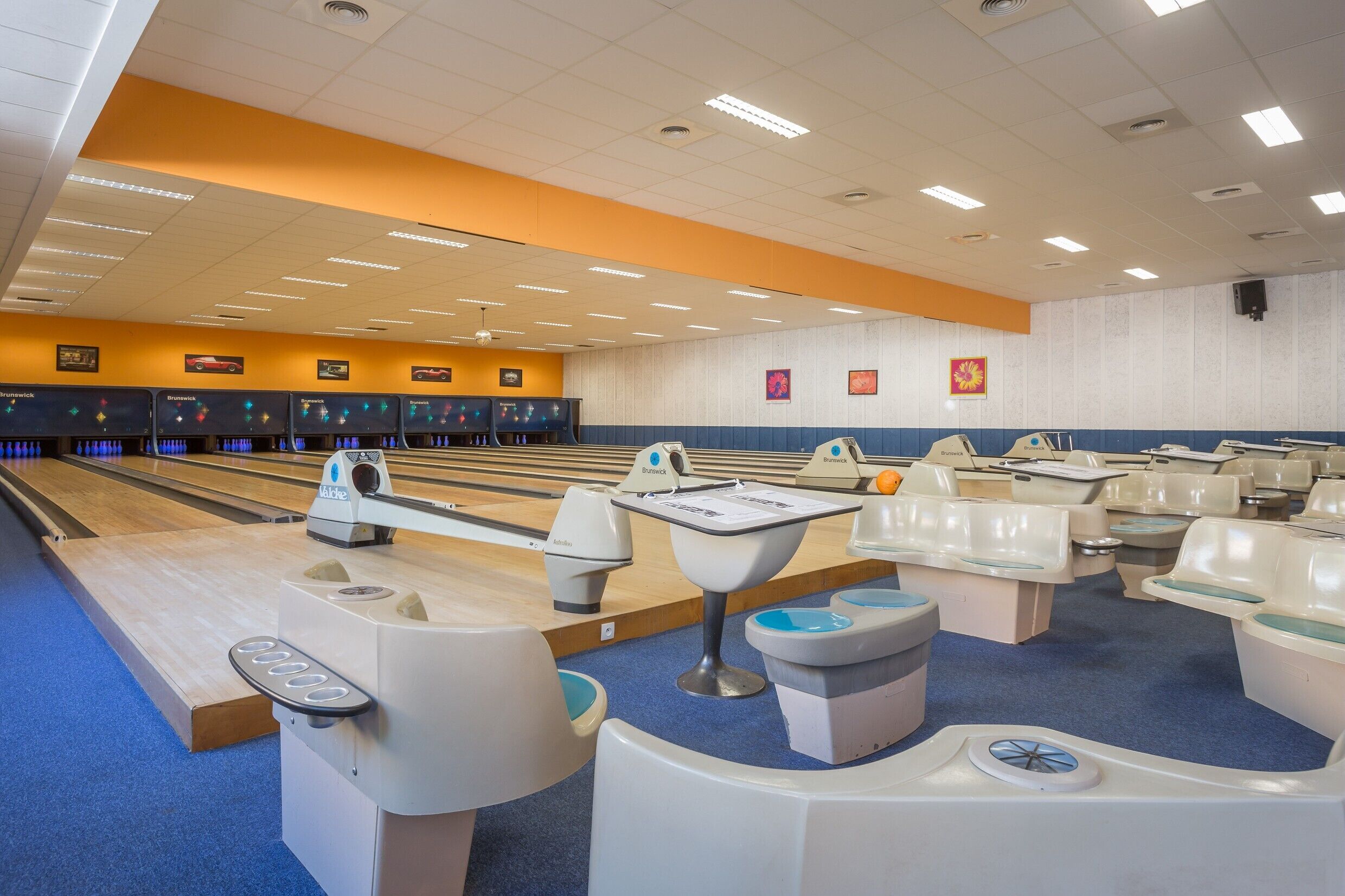 A bowling alley with multiple lanes, bowling balls, and pins.
