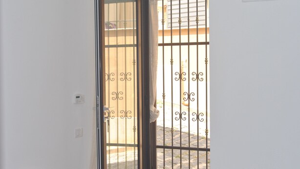 Quarto com porta de vidro deslizante que dá para área externa com portão de metal.