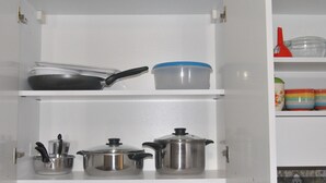 Um armário de cozinha com panelas e frigideiras.