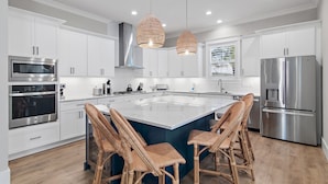 A modern kitchen with white cabinets, stainless steel appliances, and a central island with bar stools.