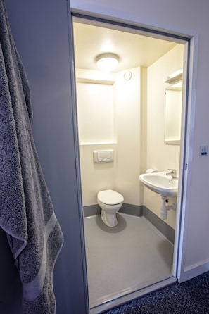 Un baño con inodoro, lavabo y toalla colgada en la pared.