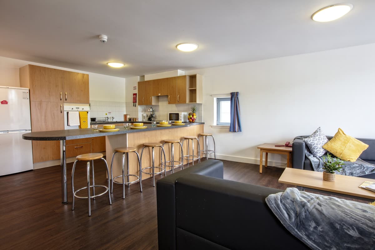 Ett modernt kök med träskåp, en köksö med barstolar och en matplats med en soffa och ett litet bord.