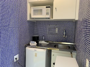 Uma cozinha compacta com micro-ondas, pia e pequena geladeira.
