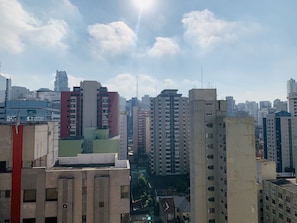 Paisagem urbana com edifícios altos, incluindo uma estrutura vermelha e bege em destaque no primeiro plano.