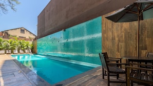 Piscina con paredes de azulejos, terraza de madera y mobiliario exterior.