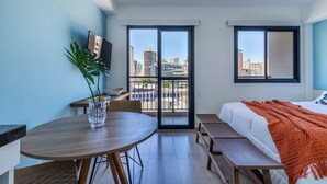 Una habitación con una cama, una mesa de comedor y un televisor en la pared.