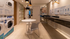 Una cocina moderna con lavadora y secadora integradas, una zona de comedor con mesa y sillas, y una lámpara colgante.