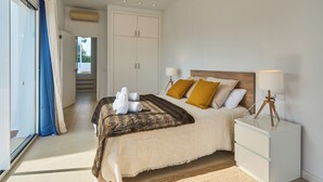 A bedroom with a bed, bedside tables, a ceiling fan, and a view through a glass door.