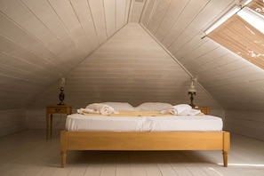 A bedroom with a sloped ceiling, a wooden bed, two bedside tables, and a window with a blind. - Villa Thalia Thassos Island Limenaria Greece (Thasos)