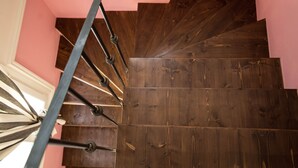 Una escalera de madera con barandilla de metal, que conduce a una pared rosa.