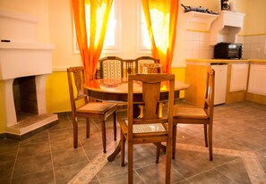 Un coin repas avec une table ronde, quatre chaises en bois et une cuisine en arrière-plan.