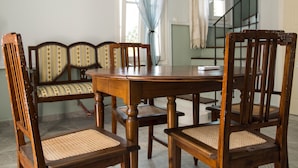 A dining area with a round wooden table and six wooden chairs with woven seats. - Villa Polimnia Thassos Island Limenaria Greece (Thasos)