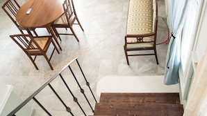 A dining area with a round table and chairs, a bench with a patterned cushion, and a staircase with wooden steps. - Villa Polimnia Thassos Island Limenaria Greece (Thasos)