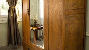 A wooden wardrobe with a large mirror, a small table, and a curtain. - Villa Polimnia Thassos Island Limenaria Greece (Thasos)