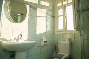 A bathroom with a sink, mirror, toilet, and window. - Villa Ourania Thassos Island Limenaria Greece (Thasos)