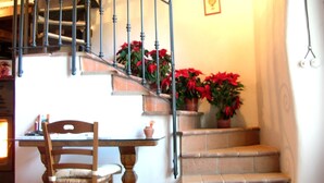 A staircase with red flowers, a wooden chair, and a table with a lamp. - Ancient Rural Tower in Tuscia Area, Near Viterbo Italy (Vignanello)