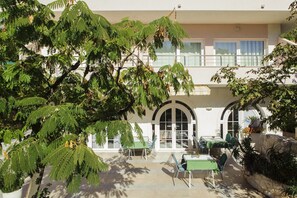 Un cortile con posti a sedere all'aperto, un muro in pietra e un edificio con finestre ad arco e balconi.