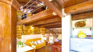 A rustic kitchen with wooden beams, a yellow sofa, a dining table, and a refrigerator. - Best Located in Alghero old Town Steps to sea Attic Emerald (Alghero)