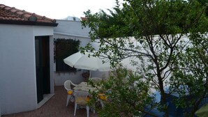 Une terrasse avec une table et des chaises, un parasol et un arbre.