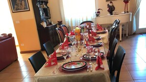 Un coin repas avec une table mise pour le repas, des chaises, un meuble contenant des objets décoratifs et un tableau accroché au mur.