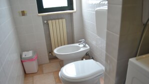 Une salle de bain équipée de toilettes, d’un bidet et d’une poubelle.